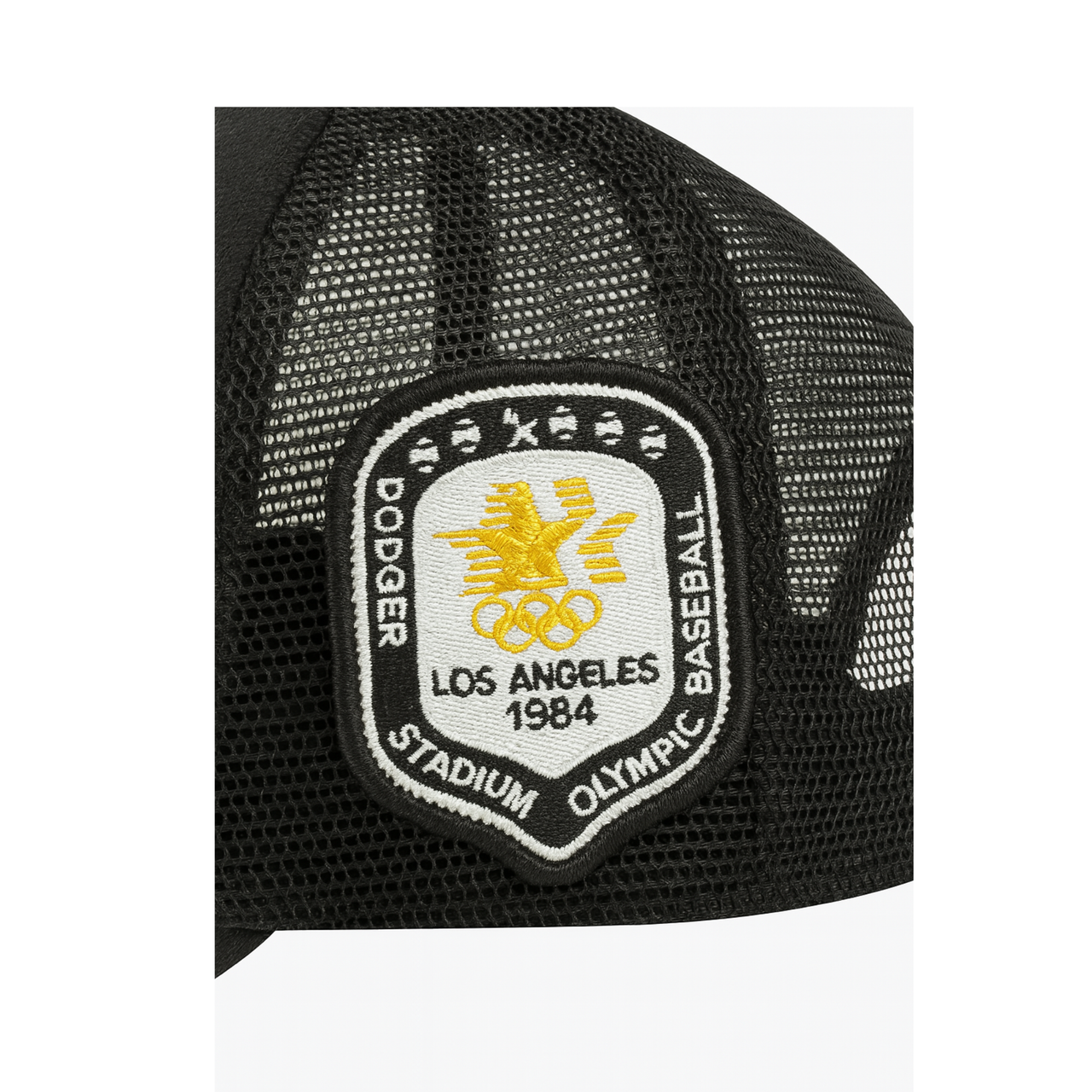 Close-up of a black mesh baseball cap featuring an embroidered 1984 Los Angeles Olympic patch with a gold Olympic emblem and text reading 'Dodger Stadium Olympic Baseball' on a white background.