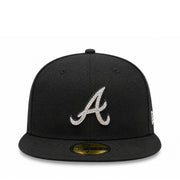 A black baseball cap featuring a silver rhinestone-embellished Atlanta Braves 'A' logo on the front, with a gold size sticker on the flat brim and a white New Era flag on the side.