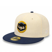A New Era 59FIFTY fitted baseball cap featuring an off-white crown with a circular embroidered black bear patch on the front, and a navy blue flat brim with a gold size sticker.