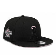 A black flat-brim baseball cap featuring the Los Angeles Angels 'A' logo in black with a pink halo on the front, and a pink and white All-Star Game patch on the side. A silver New Era sticker is visible on the brim.