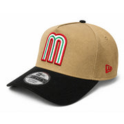A structured baseball cap with a tan crown, black visor, and a large embroidered red, white, and green 'M' logo on the front. A red New Era flag logo is visible on the side, and a black and silver size sticker is on the visor.