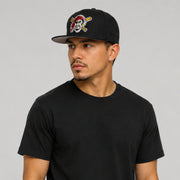Hispanic male model wearing a black New Era Pittsburgh Pirates 59FIFTY fitted hat with embroidered pirate logo and black New Era side logo