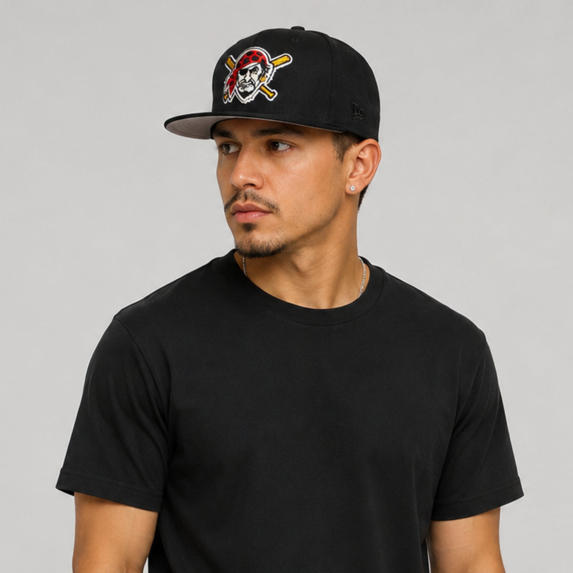 Hispanic male model wearing a black New Era Pittsburgh Pirates 59FIFTY fitted hat with embroidered pirate logo and black New Era side logo