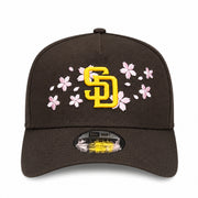 Brown cap with yellow logo and pink floral design on a white background