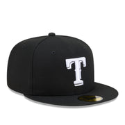 A black flat-brim baseball cap featuring a large white embroidered letter 'T' on the front, with a gold New Era sticker on the brim, set against a plain white background.